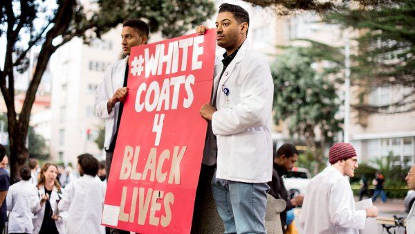 Two Students hold White Coats 4 Black Lives sign at 2015 rally