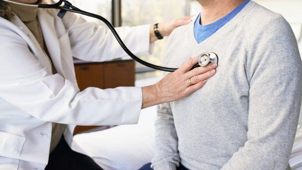doctor holds stethoscope to patient's chest