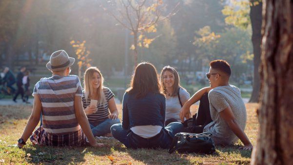 Five young adults sitting in a circle outside