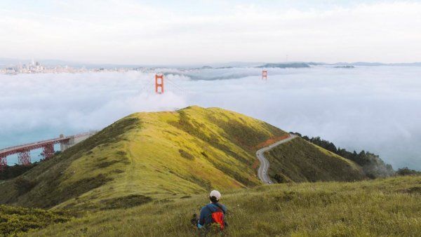 Person sitting on a grassy hill near the Golden Gate Bridge