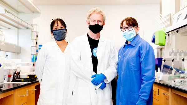 Vida Ahyong, Joe DeRisi, and Emily Crawford in face masks, lab coats, and gloves.