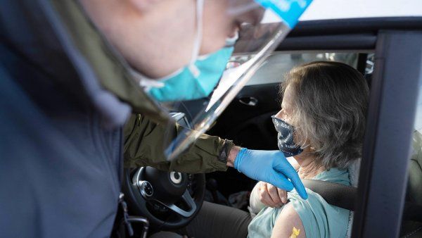 woman receives COVID-19 vaccine in her car at drive-through clinic