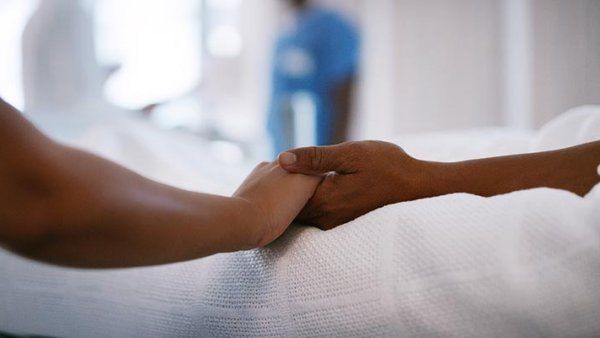 Photo of two African-Americans holding hands in a hospital setting.