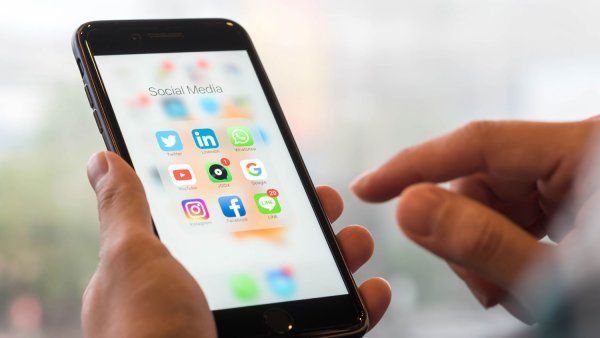 Hands holding phone with social media app icons