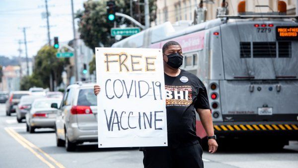 Man holding "Free COVID Vaccine" sign on street