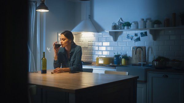 A woman drinking wine alone in a kitchen