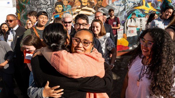 Calle 24 Latino Cultural District Executive Director Susana Rojas hugs fellow attendees while celebrating Unidos en Salud’s efforts to prevent COVID