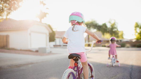 Young children riding bikes at sunset. Wearing helmest and dressed for summer.