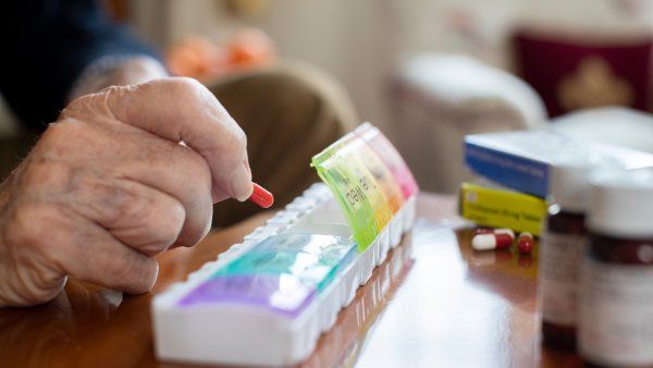 Elderly man arranging pills in a pill organizer