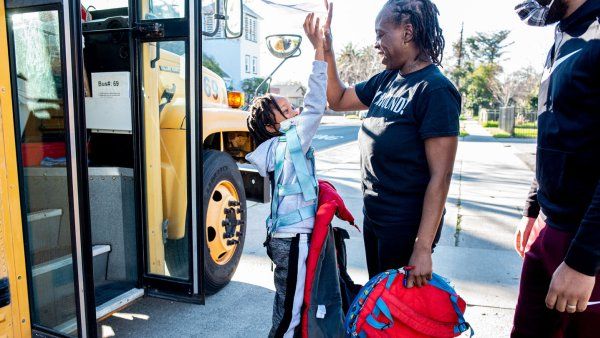 Rashetta Higgins high fives her youngest son outside of the school bus