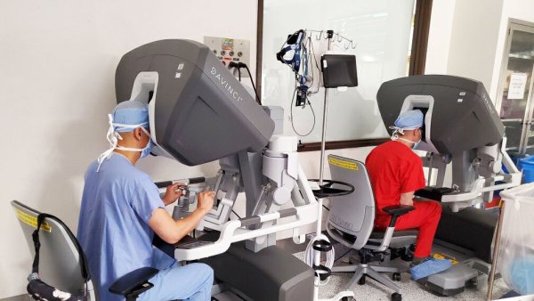 Doctors Tom C. Nguyen and Tobias Deuse in scrubs looking through 3D cameras as they perform robotic cardiac surgery 