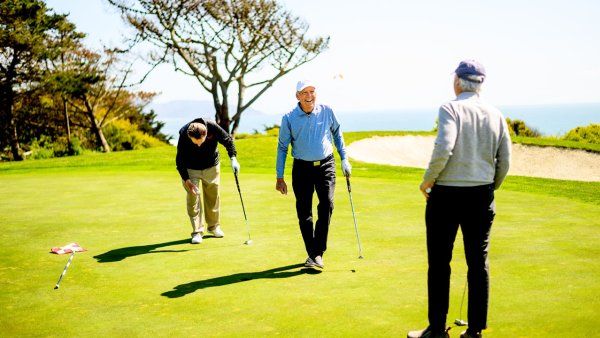 Don Onken walks between two friends on the golf course while laughing