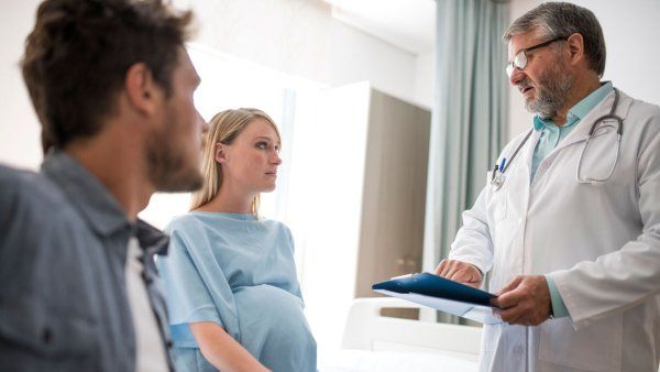 Doctor speaking with pregnant woman sitting with man