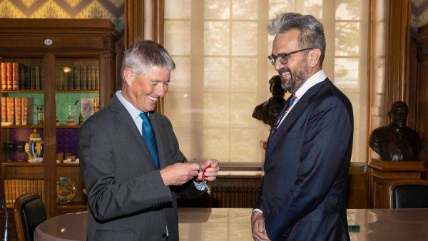 Stewart Cole, President of Institut Pasteur, prepares an award lapel pin for Nevan Krogan (right)