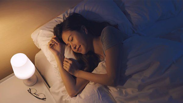 A woman sleep serenely in bed with a nightlight 