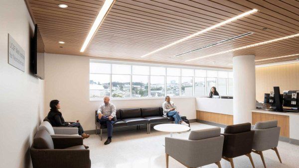 A comforting, light-filled reception area. A few people sit in modern grey and blue chairs.