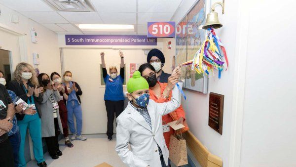 A young male patient named Manwar rings a bell at his remission celebration, along with his parents.