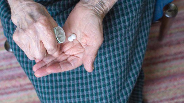 Elderly homeless person taking pill medication.