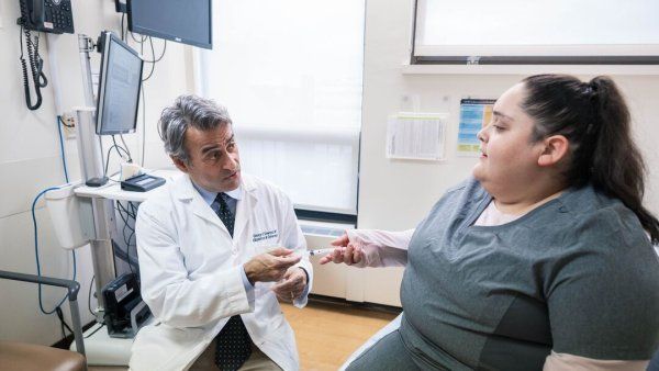 Dr. George Sawaya explains an at-home H P V screening device to a patient.