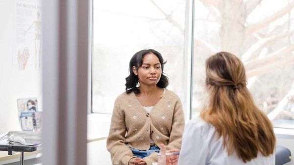 A teenage girl meets with a doctor.