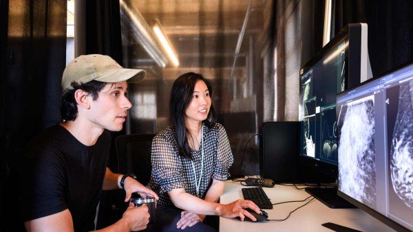 Researchers Maggie Chung and Adam Yala look at a mammogram scan on a computer screen.