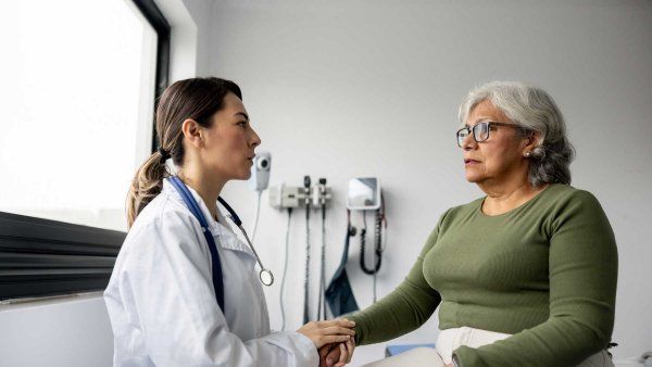 A doctor comforts an elderly female patient.