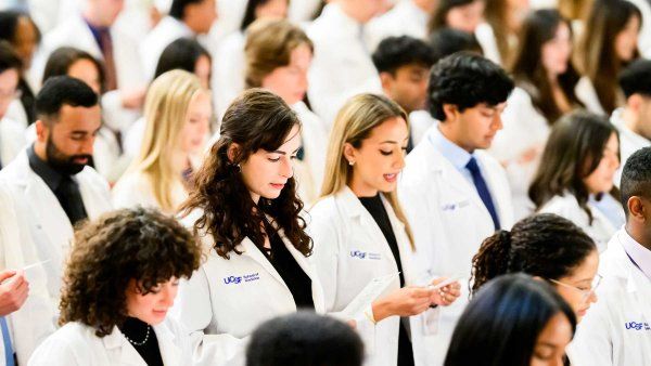 Medical students wearing white coats recite an oath.