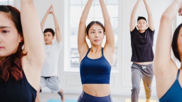 Five people in yoga class, standing and stretching their arms