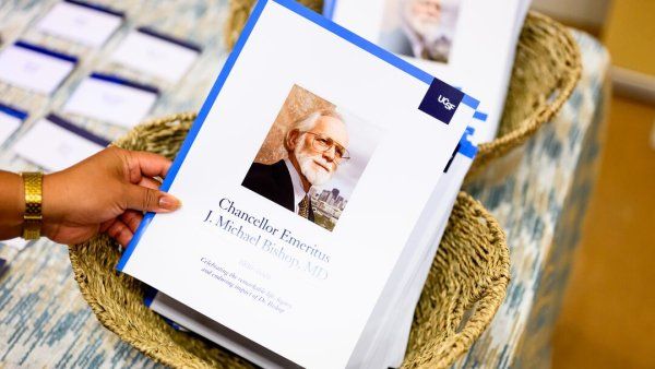 A woman's hand picks up a printed program for J. Michael Bishop's memorial.