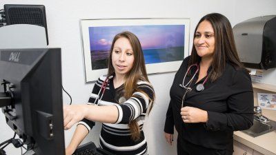 Family nurse practitioner student Lilly Chavez looks at a computer with her preceptor, Elizabeth Castillo
