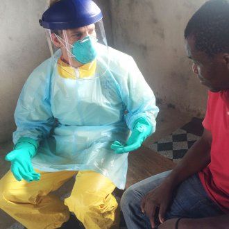 Man in hazmat suit speaking with ebola patient 