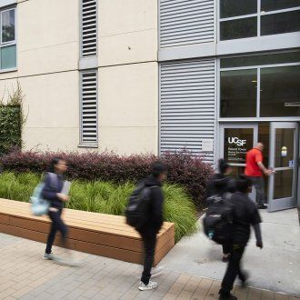 Students walking toward the entrance of a housing tower on the Mission Bay campus