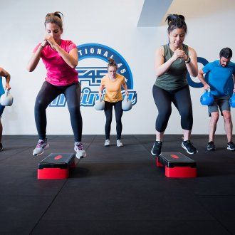 Class participants jumping off an exercise step