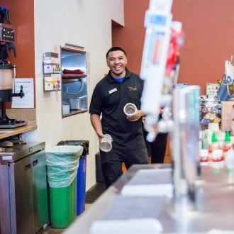 A bartender laughing as he walks behind the bar at The Pub