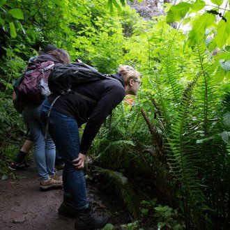 Alexandra Lepeschkin-Noel bends down to look at a native plant during a wildflower walk