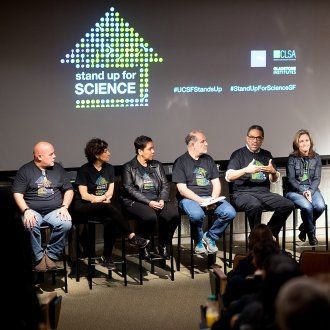 Andre Campbell speaks during a Stand Up for Science teach-in with a row of panelists