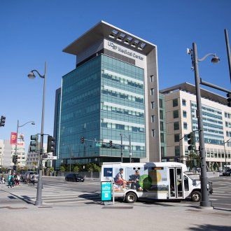 A shuttle turns in front of the medical tower at the end of the UCSF Medical Center at Mission Bay