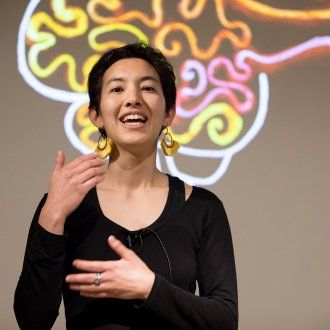 Tess Veuthey presents her 3-minute thesis at the 2018 Grad Slam with a colorful brain projected behind her