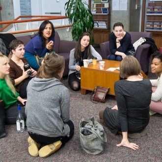 A group of nursing students sit in a circle on both chairs and the floor