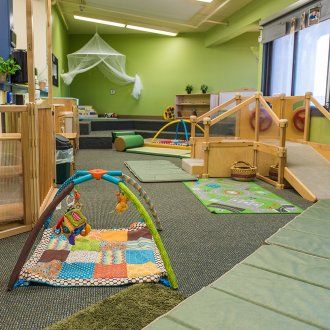 Toys, floors mats and climbing equipment in a green-walled classroom