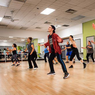 Dancers move their arms up while they step to the right during a Zumba Class