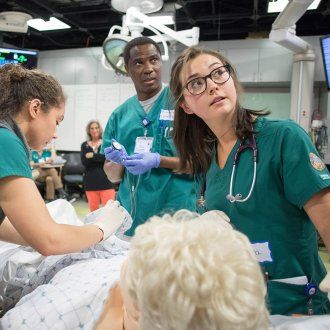 Three students tackle a simulated medical emergency in the Kanbar Center