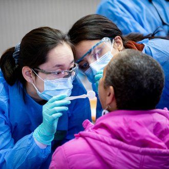 At a community health fair two dentists examine a community member for free