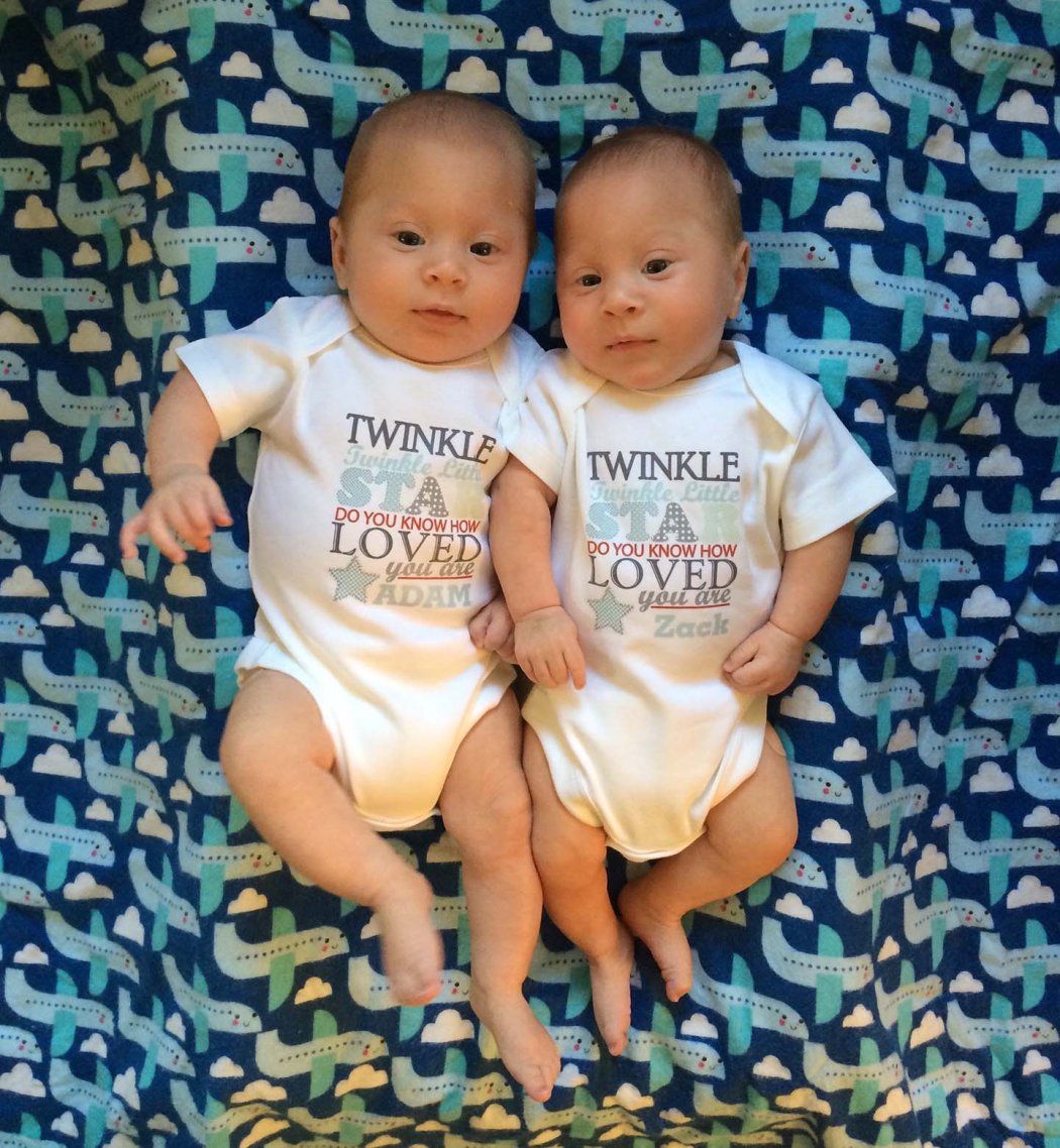 Two twin infants lie side by side peacefully wearing onesies that read Twinkle Twinkle Little Star Do You Know How Loved You Are