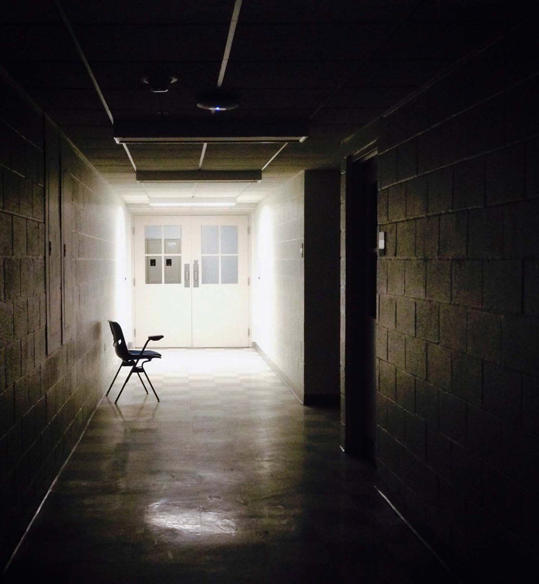 A dark school hallway with an empty chair.