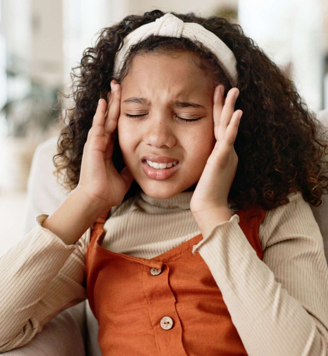 12 year old girl hold head in pain.