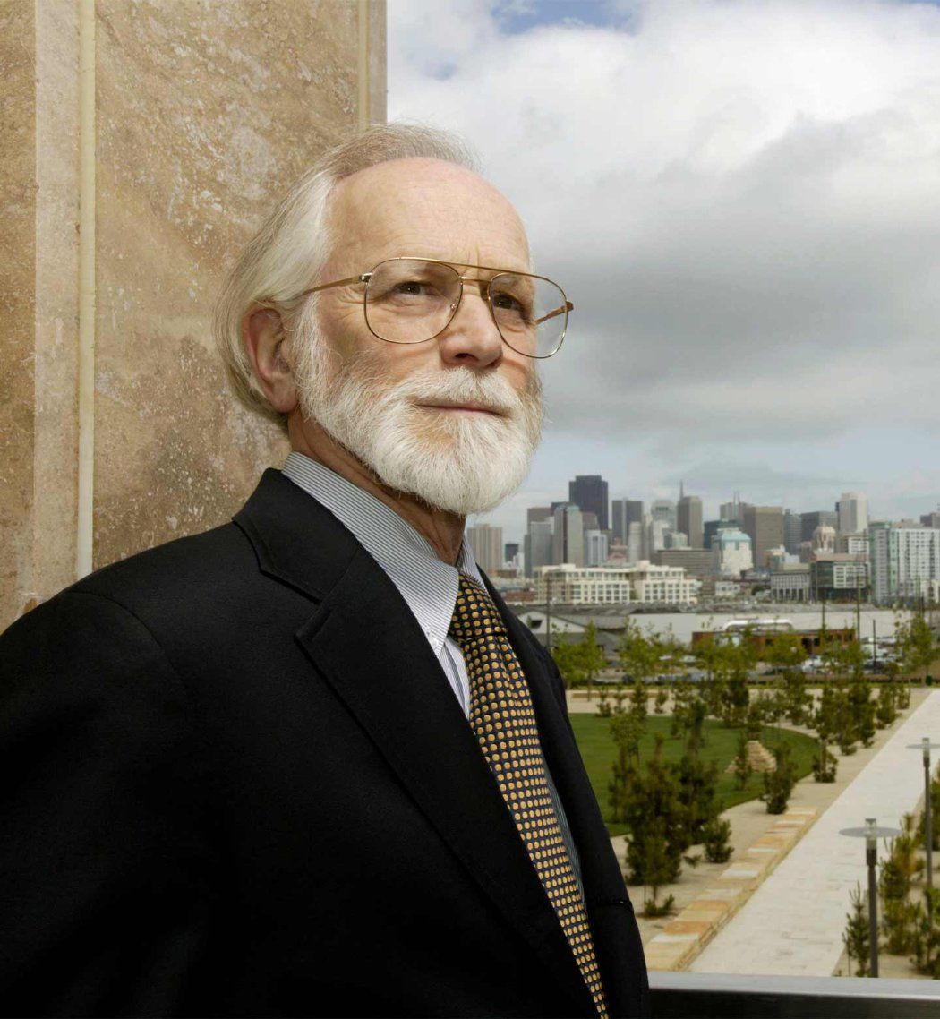 U C S F Chancellor Emeritus Michael Bishop stands outdoors with downtown San Francisco in the background.
