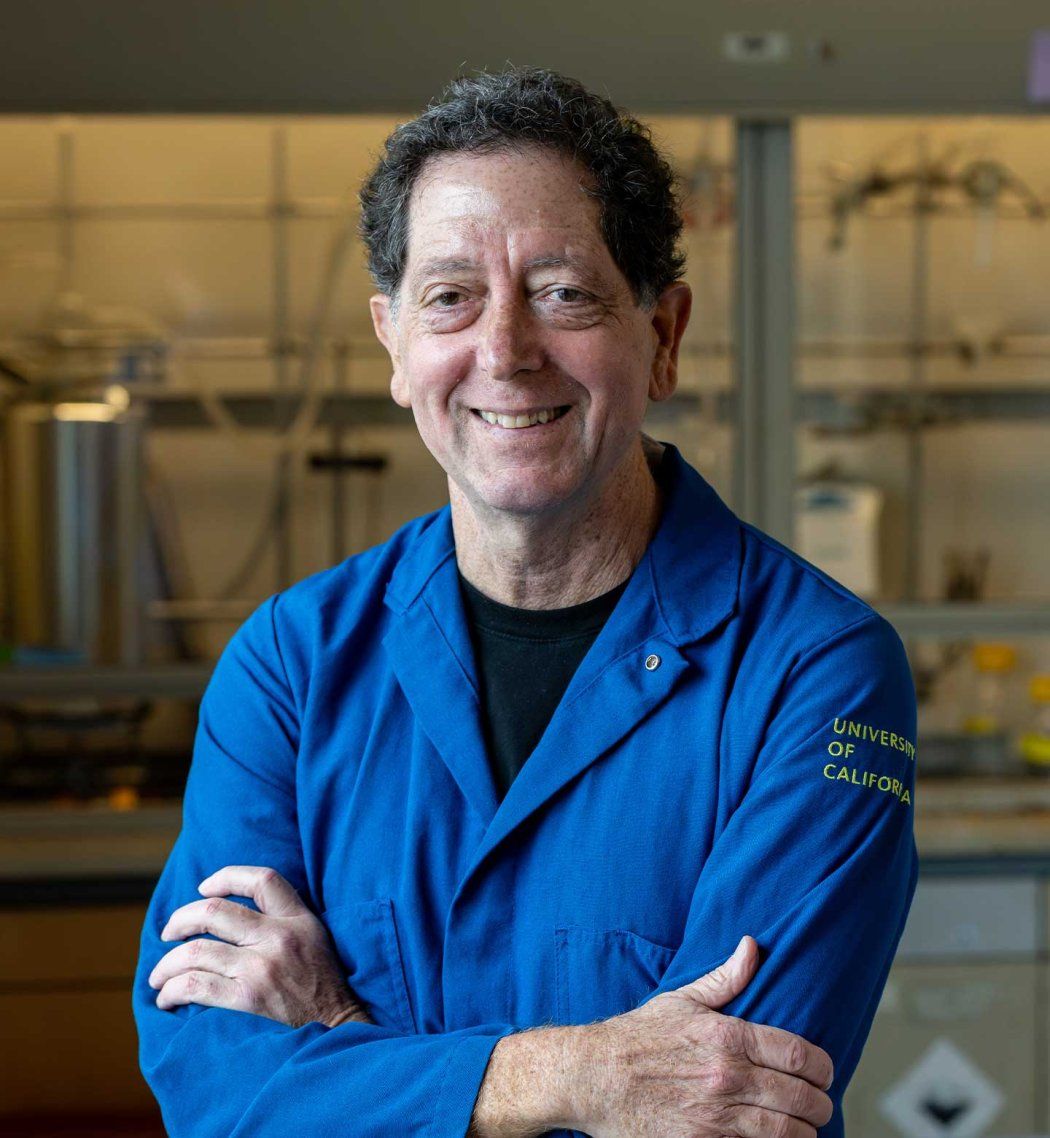 Kevan Shokat wears a blue lab coat as he stands in his lab at U C S F.