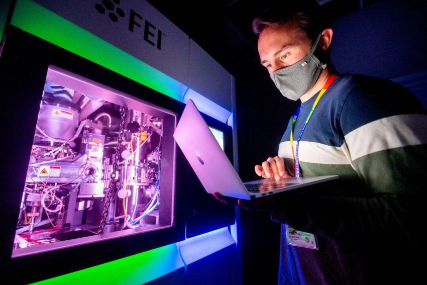 Aashish Manglik holds a laptop while operating a cryo-electron microscope