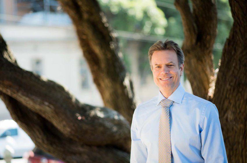 Tobias Deuse smiles for a portrait near a tree